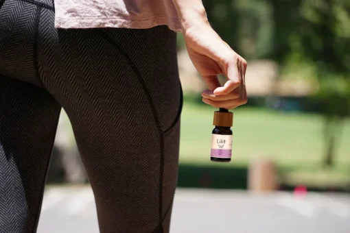 una mujer pasea por el parque con aceite cbd en la mano