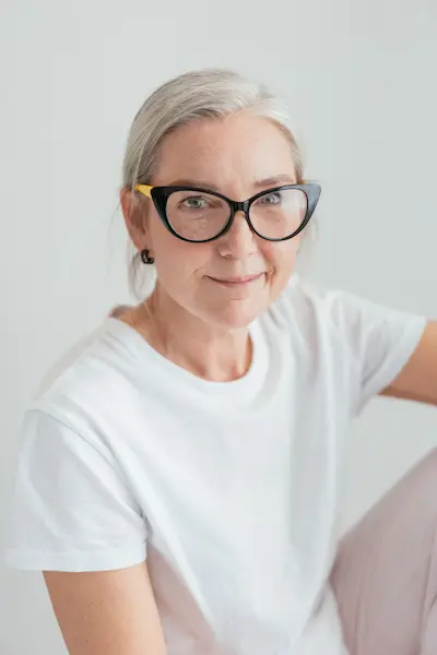 mujer menopausia con gafas camiseta blanca pelo blanco